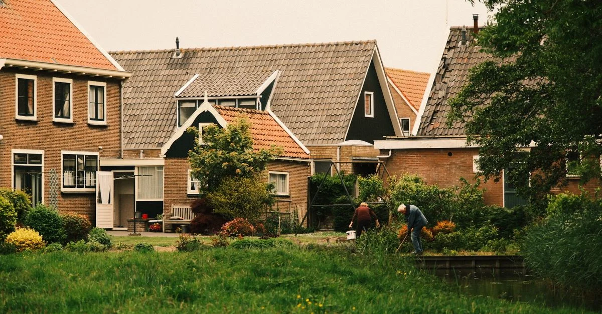 Vue pittoresque de maisons de banlieue néerlandaises avec des jardins luxuriants et des gens qui jardinent.
